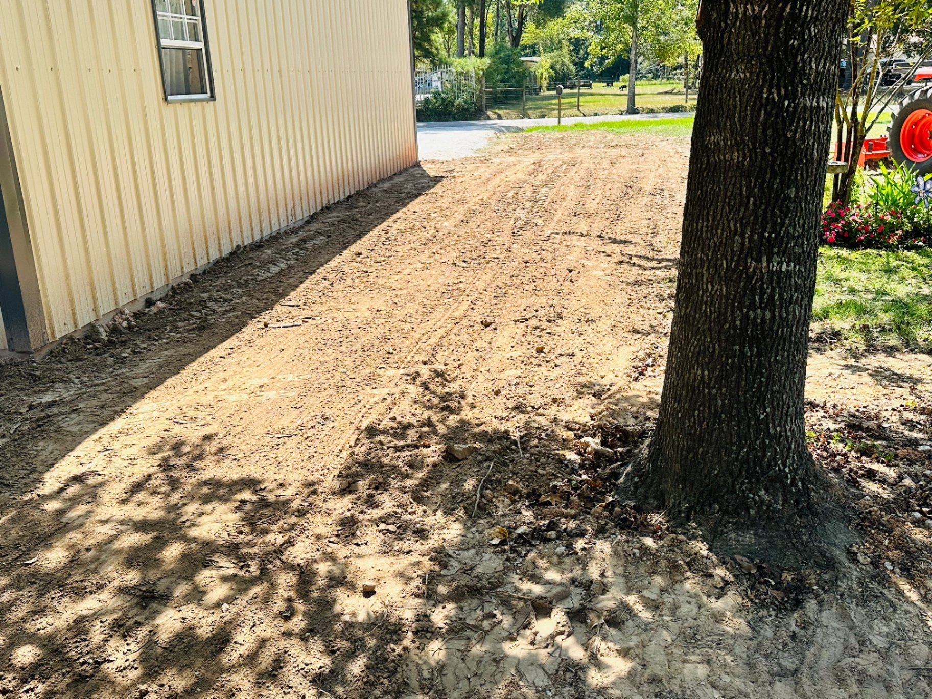 Graded dirt strip alongside a metal shop building