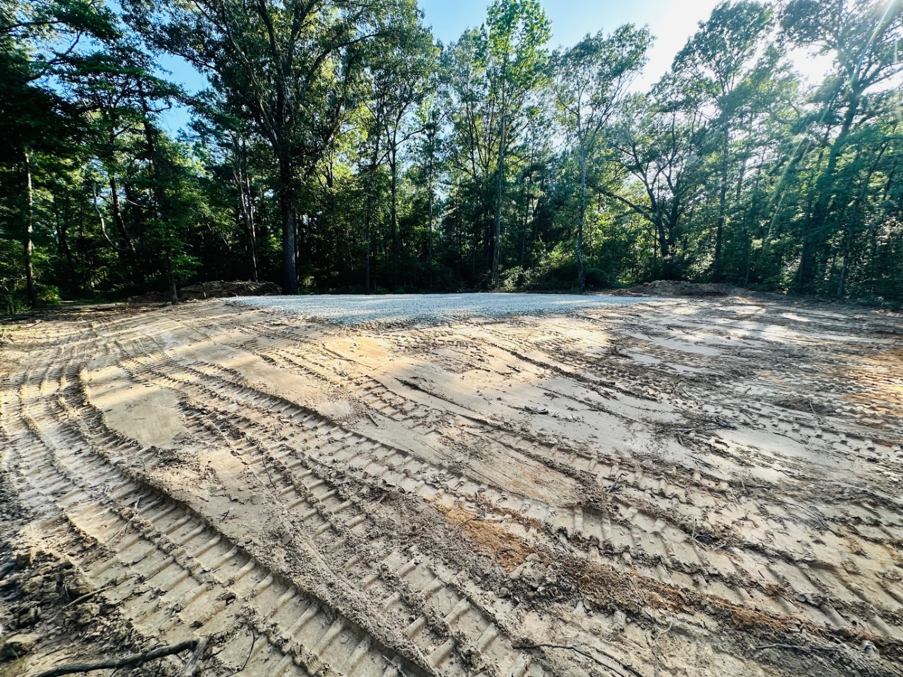 Freshly compacted building pad with track marks and gravel