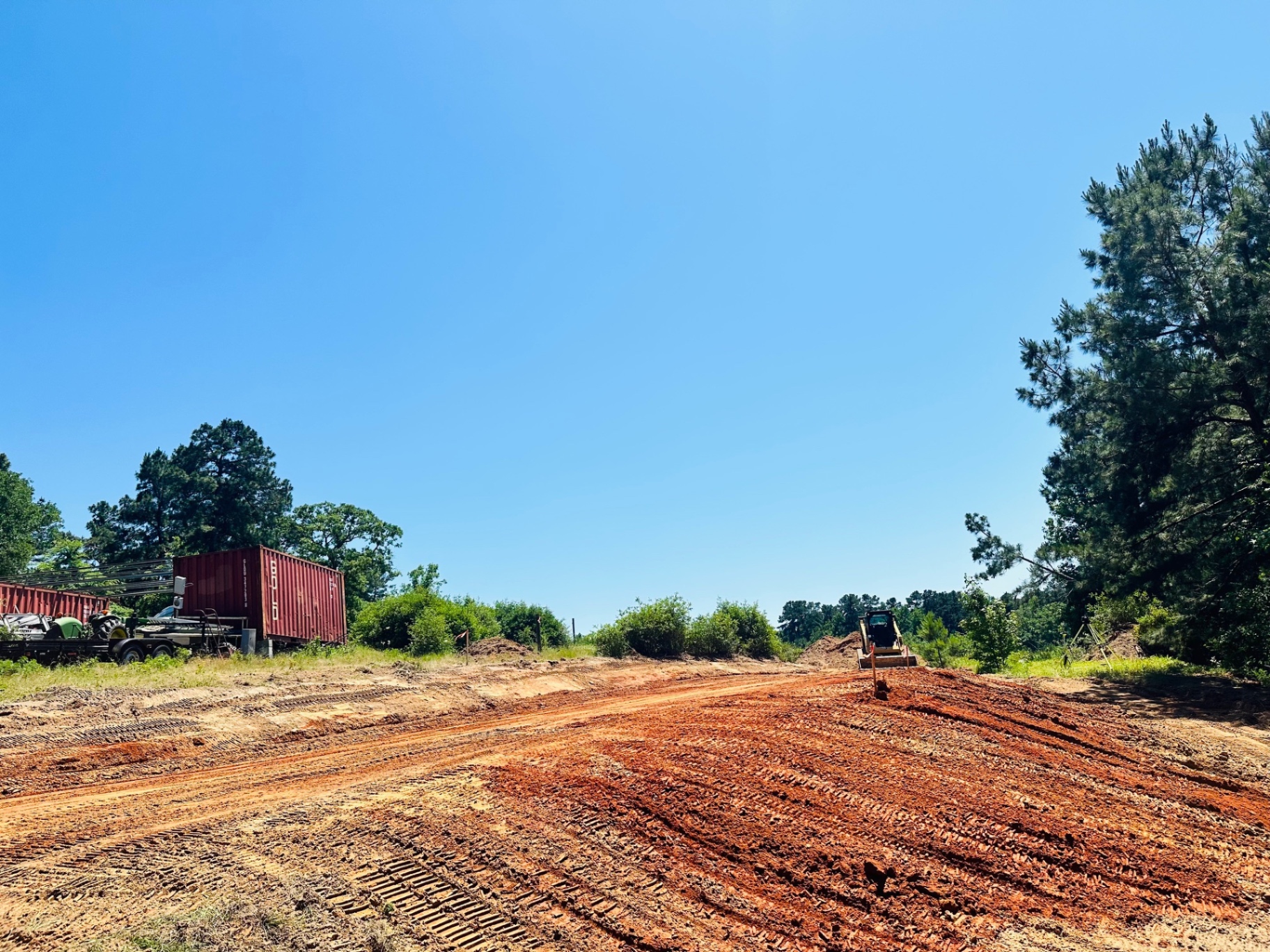 Fresh red-dirt building pad graded by skid steer