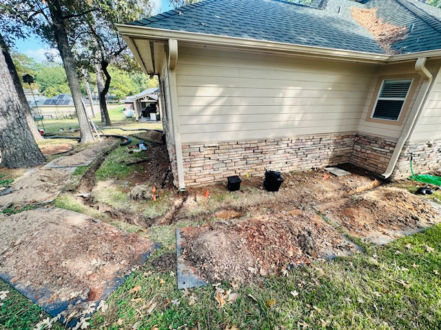 Downspout drainage trenches dug along the side of a home